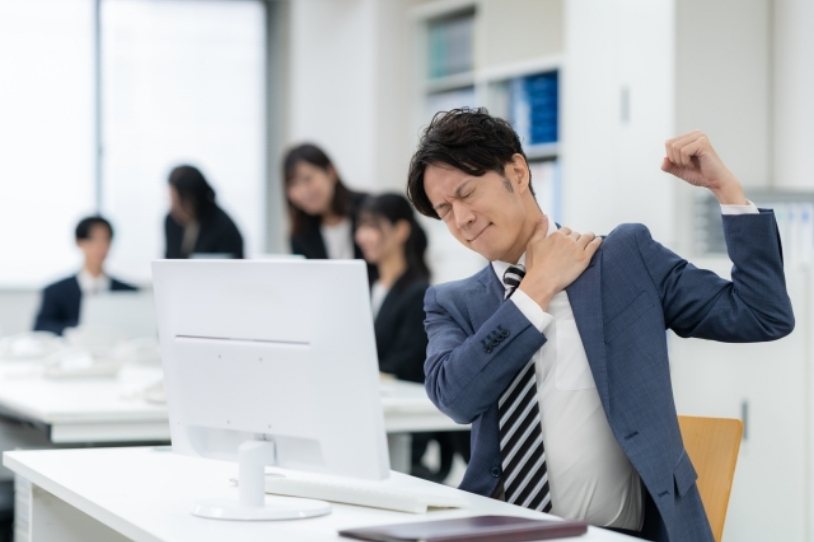 デスクワークで肩こりに悩む男性